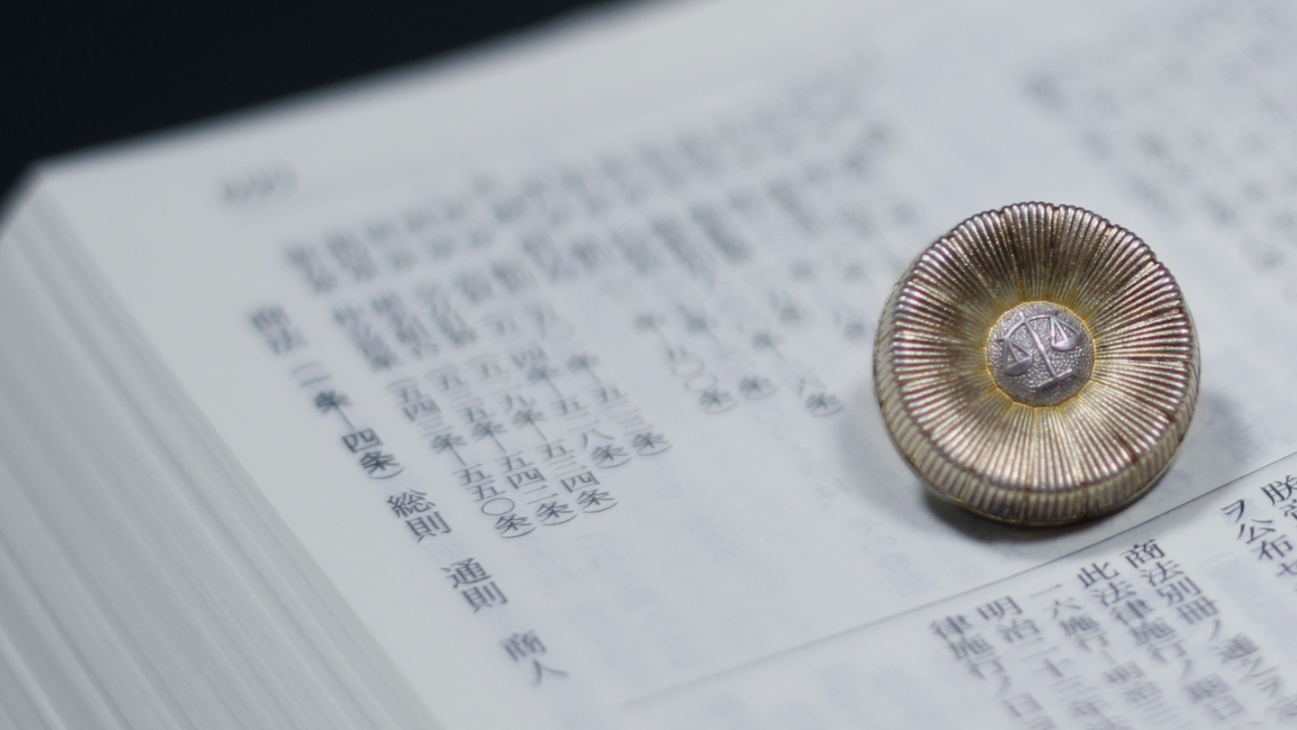 開いた法令集の上に置かれた弁護士記章